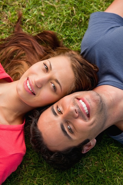 Primer plano de dos amigos sonriendo mientras se está acostado de cabeza a hombro