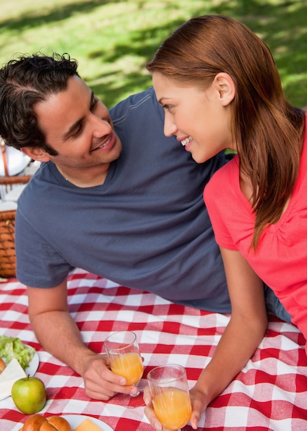Primer plano de dos amigos sonrientes acostado sobre una manta con un picnic
