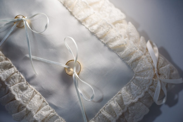 Primer plano de dos anillos de boda en una almohada roja