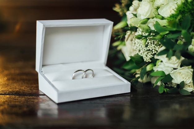 Primer plano de dos anillos de boda de lujo en una elegante caja blanca sobre la mesa. Accesorios de boda