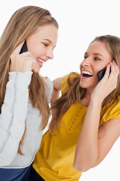 Primer plano de dos hermosos estudiantes riendo en el teléfono