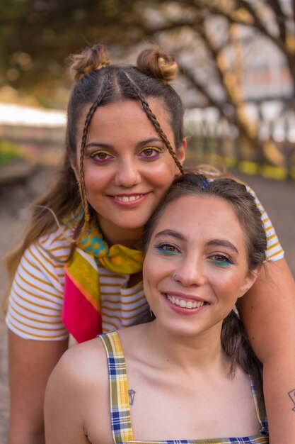 Un primer plano de dos jóvenes mujeres caucásicas abrazando con bandera de orgullo LGBT al aire libre