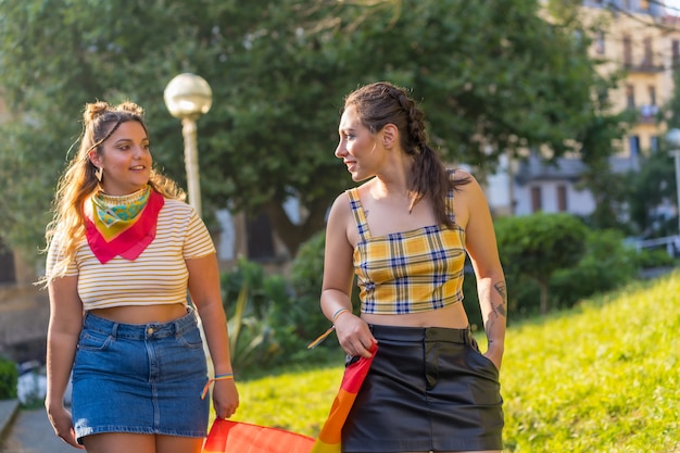 Un primer plano de dos jóvenes mujeres caucásicas sosteniendo la bandera del orgullo LGBT al aire libre