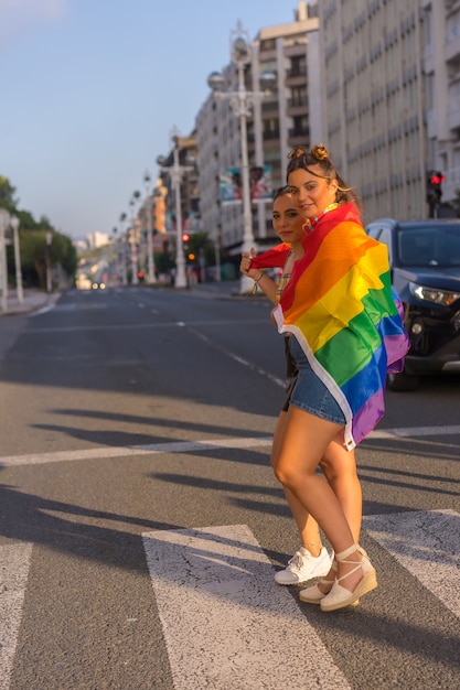 Un primer plano de dos jóvenes mujeres caucásicas sosteniendo la bandera del orgullo LGBT al aire libre