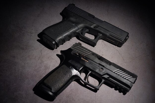 Primer plano de dos pistolas automáticas de metal negro de 9 mm colocadas sobre un fondo negro