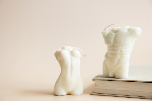 Foto primer plano de dos velas hechas a mano de cera de soja en forma de torso de hombre y cuerpo de mujer aislado sobre fondo beige pastel