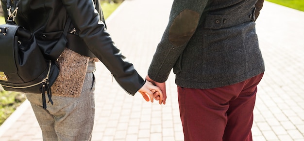 Primer plano, de, elegante, pareja, enamorado, manos de valor en cartera, en la calle, vista trasera