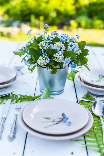 Primer plano elegante ramo de flores en azul nomeolvides una mesa rústica blanca.