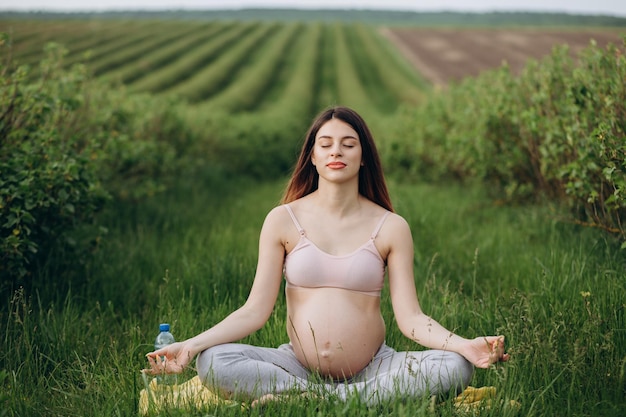 Primer plano de una encantadora mujer embarazada haciendo ejercicios de yoga en el parque