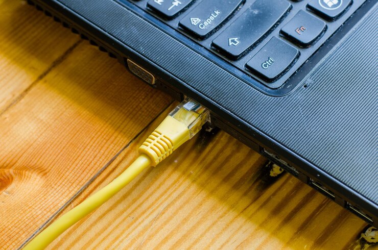Foto primer plano del enchufe de conexión de red conectado a la computadora portátil en la mesa