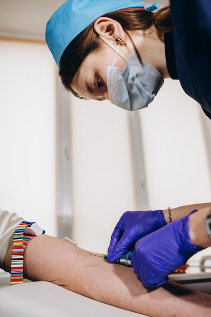 Primer plano de la enfermera desinfectando el brazo masculino antes del análisis de sangre El hombre está sentado en una silla cerca del equipo médico