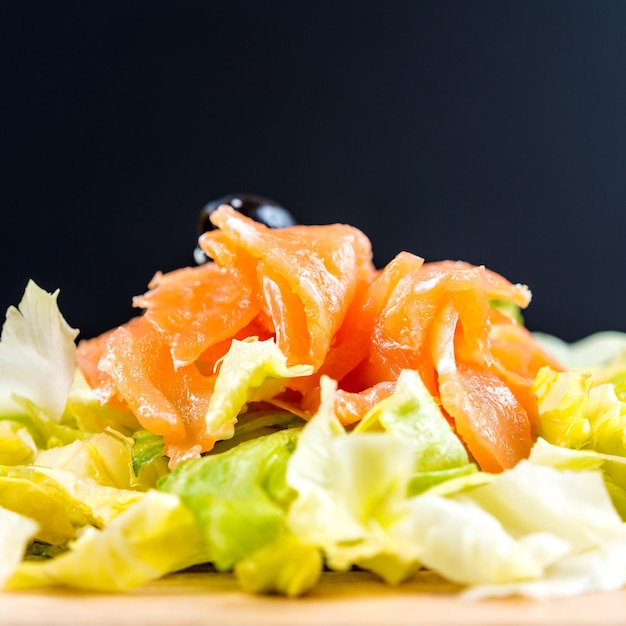 Primer plano de una ensalada de salmón en la mesa contra un fondo negro