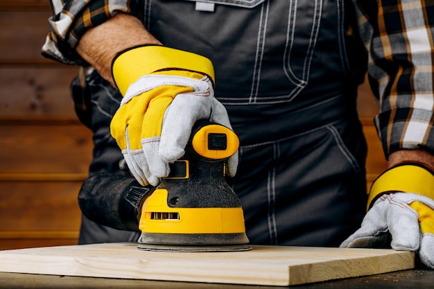 Primer plano de enviar una madera con lijadora orbital en el taller