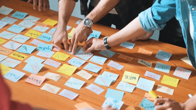Un primer plano de un equipo de desarrolladores inteligentes usando un mapa mental para una tormenta de ideas Simposio