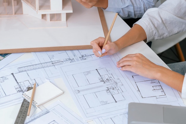 Primer plano del equipo de ingenieros trabajando juntos para medir el modelo de casa inmaculado