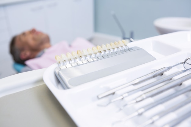 Primer plano de equipo médico en la mesa contra el hombre acostado en la silla del dentista