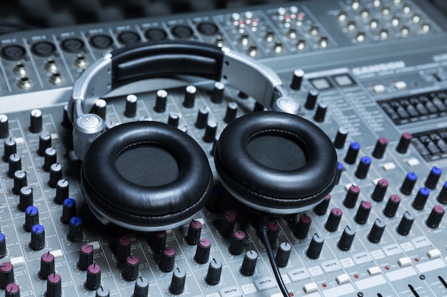 Primer plano del escritorio de control del estudio de grabación boutique, auriculares dj para disco profesional, equipo para estudio de grabación de sonido, mezclador y auriculares para DJ