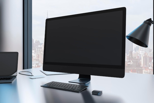 Primer plano del escritorio de diseñador creativo con monitor de computadora negro vacío y suministros en la oficina moderna con ventana y vista panorámica de la ciudad Representación 3D