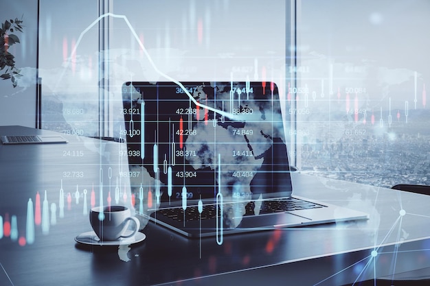 Primer plano del escritorio de la oficina con una taza de café portátil vista borrosa de la ciudad y gráfico de forex de velas brillantes y holograma de mapa sobre fondo borroso Mercado de inversión bursátil y concepto de dinero Doble exposición