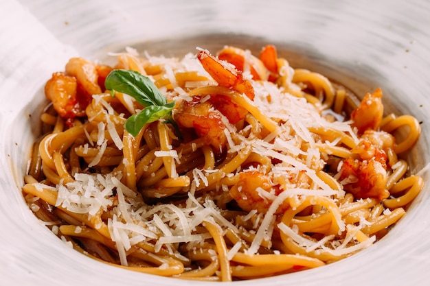 Primer plano de espaguetis con camarones rebozados y parmesano