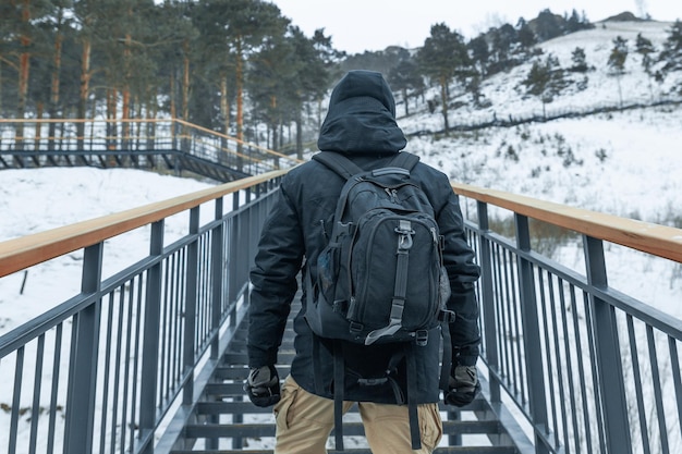 Primer plano de la espalda de un turista con una mochila subiendo las escaleras que conducen a la montaña. Fin de semana de caminata de invierno.