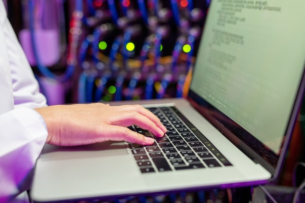 Primer plano de un especialista en redes femenino irreconocible escribiendo en la computadora portátil mientras se actualiza el software