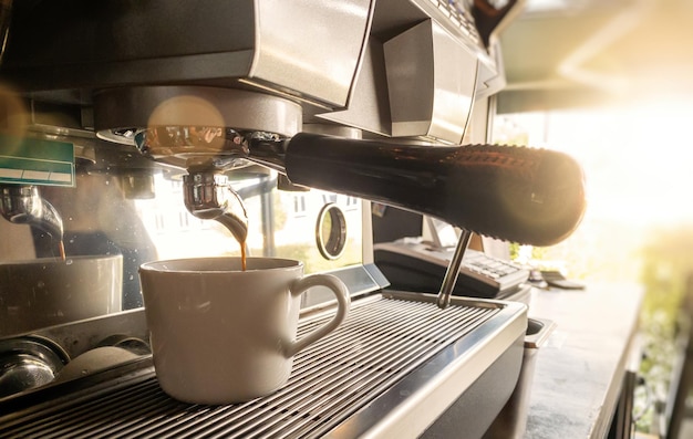 Primer plano de un espresso que se vierte de una máquina de café por parte de la elaboración de café profesional