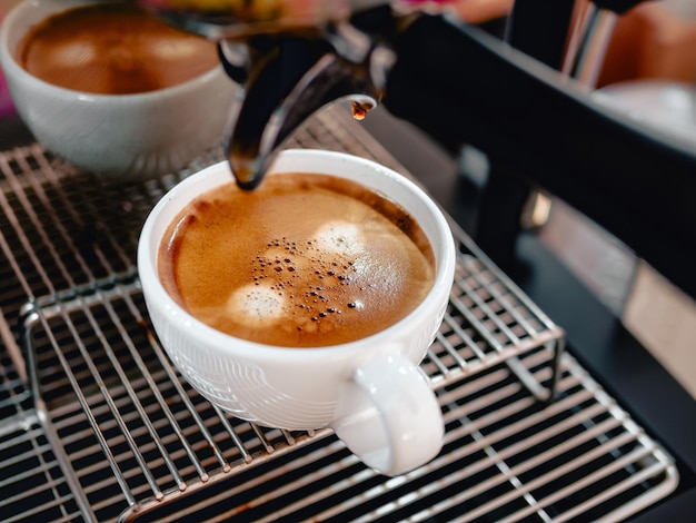 Foto primer plano de un espresso que se vierte de la máquina de café en una taza de café café profesional