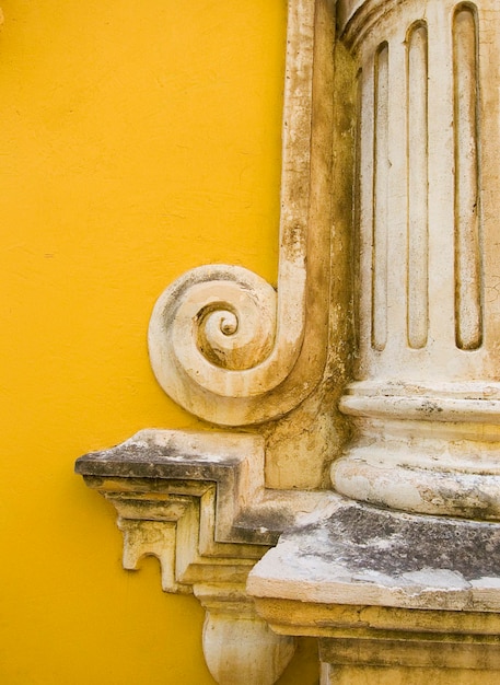 Foto primer plano de la estatua contra la pared amarilla