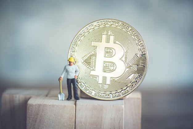 Primer plano de una estatuilla de trabajador masculino con bitcoin en madera