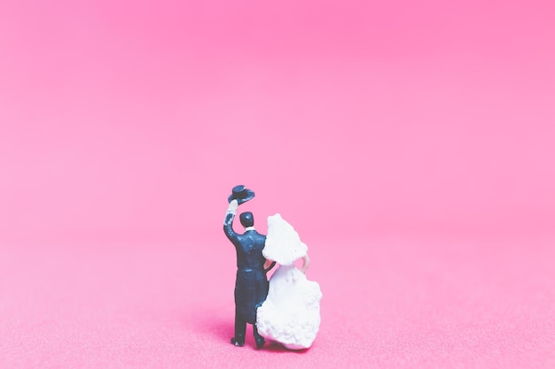 Foto primer plano de las estatuillas de la boda sobre un fondo rosado