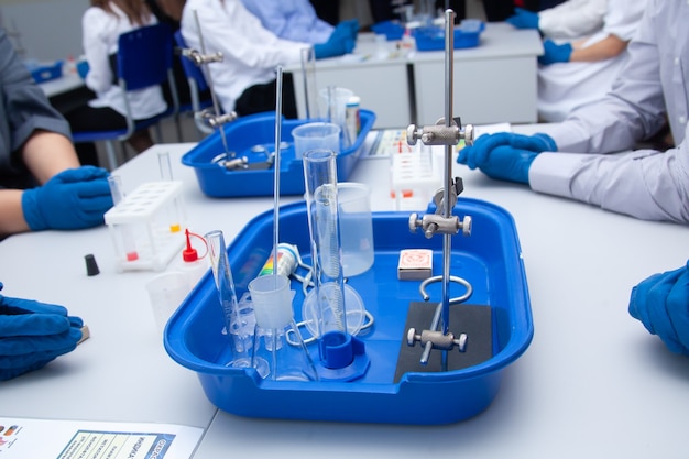 Primer plano de la experiencia química. Las manos enguantadas sostienen un frasco de líquido. Experimentos escolares. Lecciones de química. Laboratorio. Foto de alta calidad