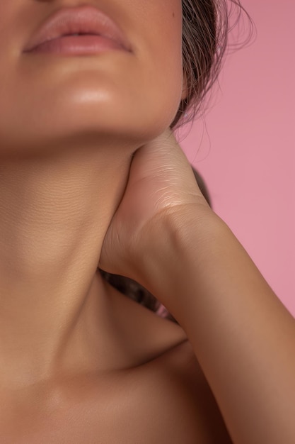 Foto primer plano extremo del cuello y los labios de la mujer contra un fondo rosa