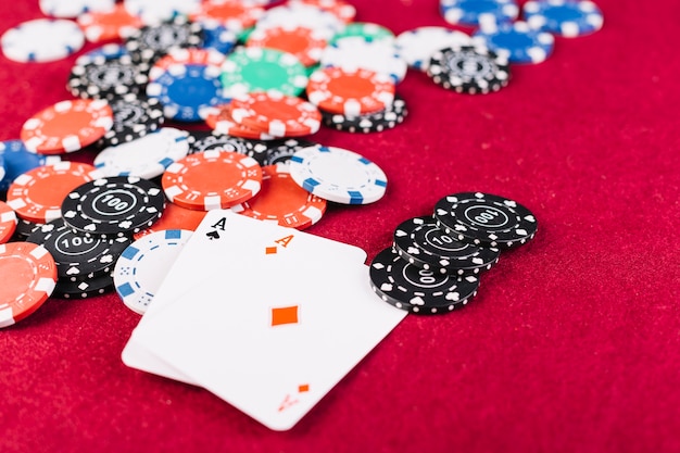 Primer plano de fichas de colores y dos ases jugando a las cartas en la mesa de póquer
