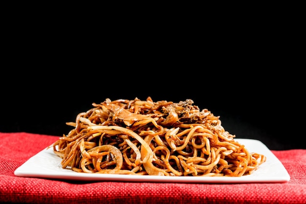 Foto primer plano de fideos fritos en la mesa contra un fondo negro