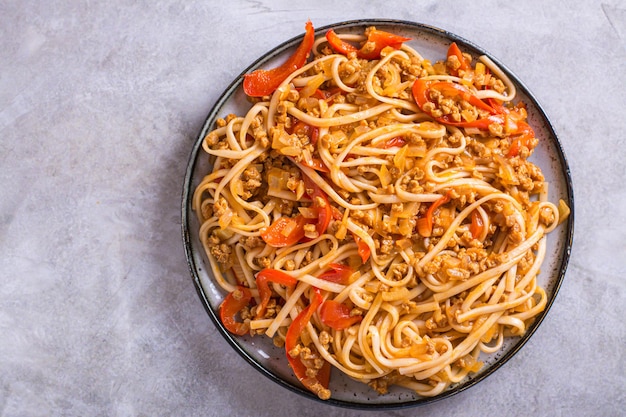 Primer plano de fideos udon con carne de soja y verduras en un plato en la vista superior de la mesa