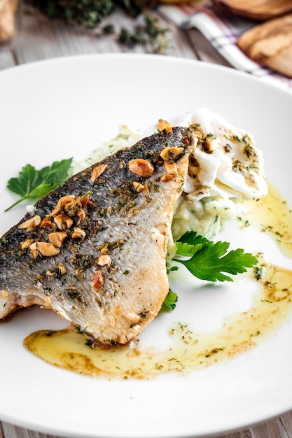 Primer plano de filete de pescado cocido con puré de patatas y huevo escalfado