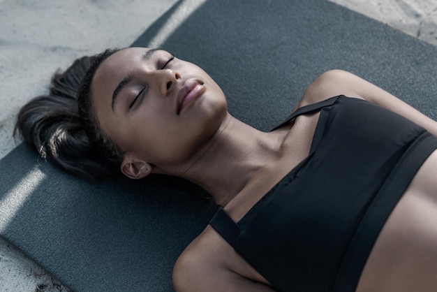 Primer plano de fitness joven descansando después de hacer ejercicio al aire libre en la playa