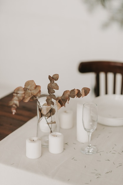 Primer plano de flores artificiales en un jarrón sobre una mesa con un mantel blanco