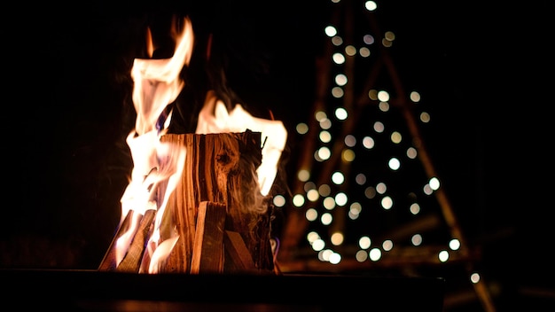 Foto primer plano de una fogata frente a las luces de navidad borrosas