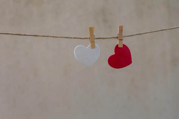 Primer plano en forma de corazón rojo colgando de una cuerda contra la pared
