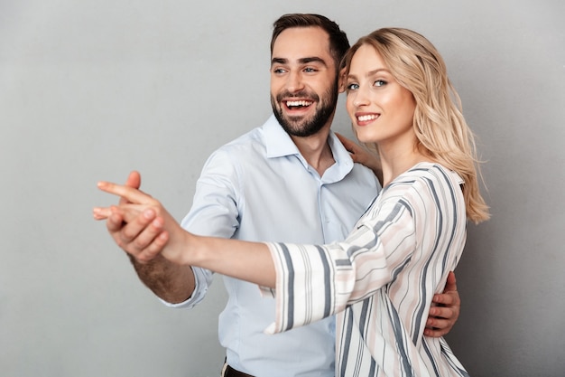 Primer plano de la foto de la pareja sonriente en ropa casual bailando aislado sobre pared gris