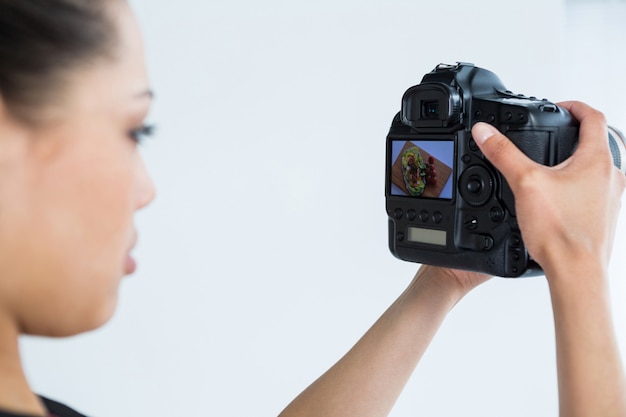 Primer plano de una fotógrafa revisando fotos capturadas en su cámara digital