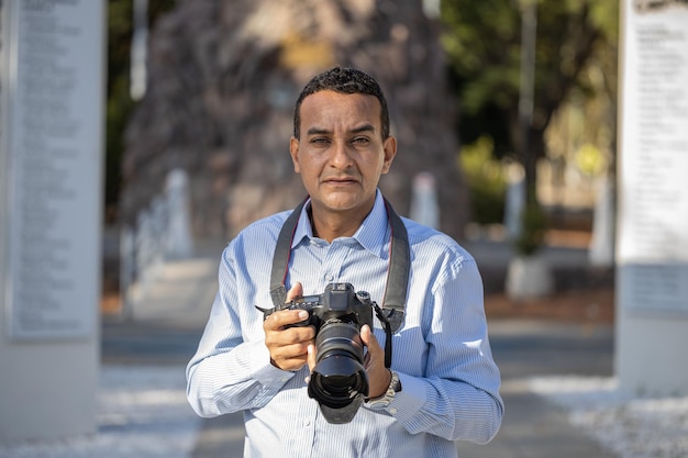 Primer plano del fotógrafo mirando al frente con su cámara en la mano