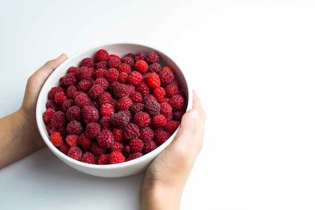 Primer plano de frambuesas frescas en una taza blanca, los beneficios de las vitaminas naturales para los niños son