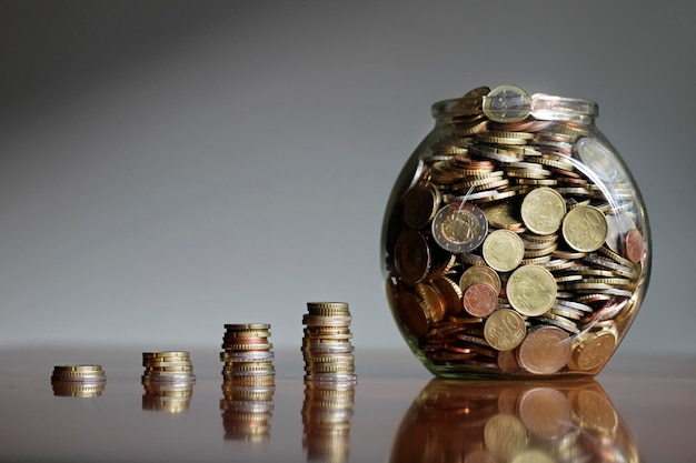 Primer plano de frascos con monedas en la mesa contra un fondo gris