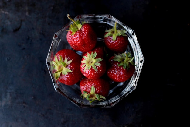 Primer plano de fresas en un cuenco contra un fondo negro