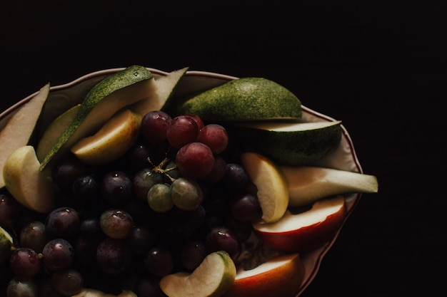 Primer plano de frutas en un cuenco contra un fondo negro