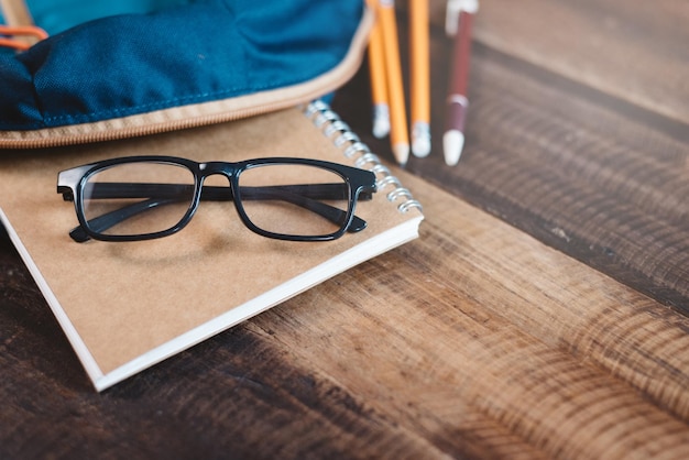 Foto primer plano de gafas con artículos escolares en una mesa de madera