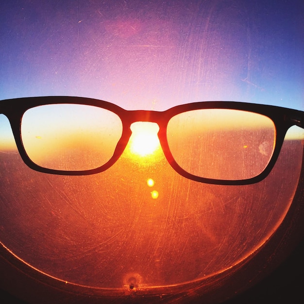 Foto primer plano de gafas frente a la ventana del avión al atardecer